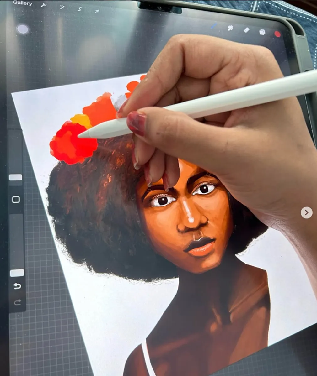 A portrait of a woman with an afro and orange blossoms being painted in Procreate on an iPad, stylus in hand.